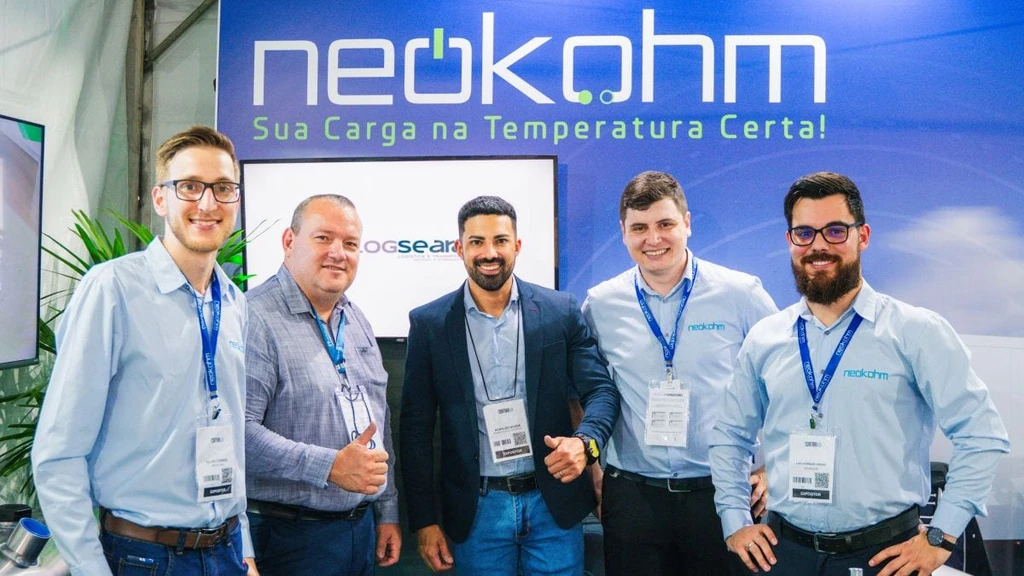 Cinco homens posam sorrindo sob o grande logotipo da Neokohm, dois deles com o polegar para cima e três de camisa azul-clara da marca