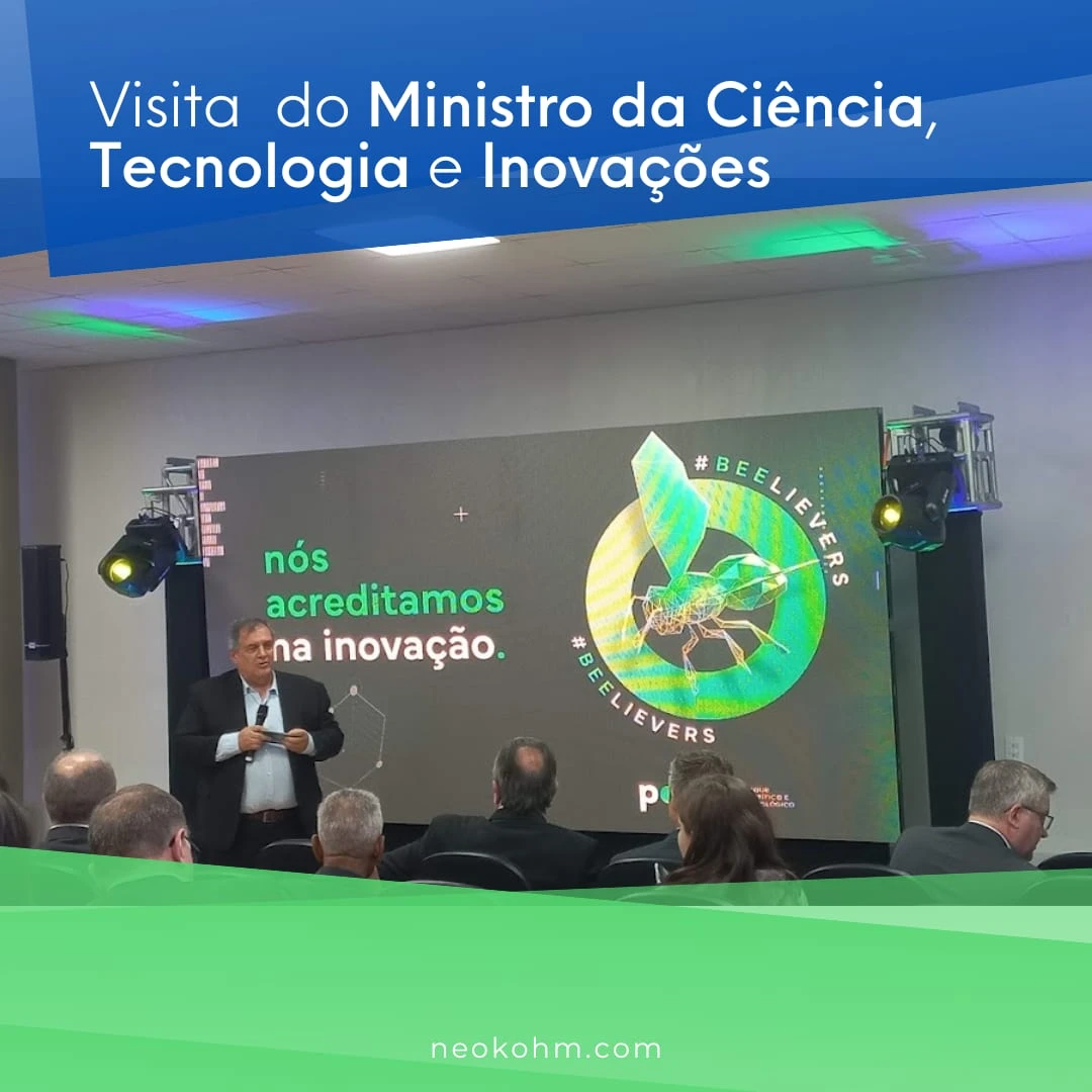 Homem de terno, com microfone na mão, fala a uma plateia diante de telão com a frase "nós acreditamos na inovação."