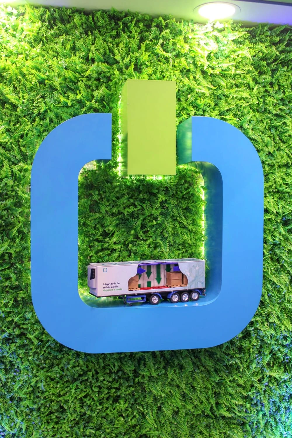 Símbolo da Neokohm em um jardim vertical, com uma miniatura de carreta refrigerada, no estande da Fetranslog 2025.