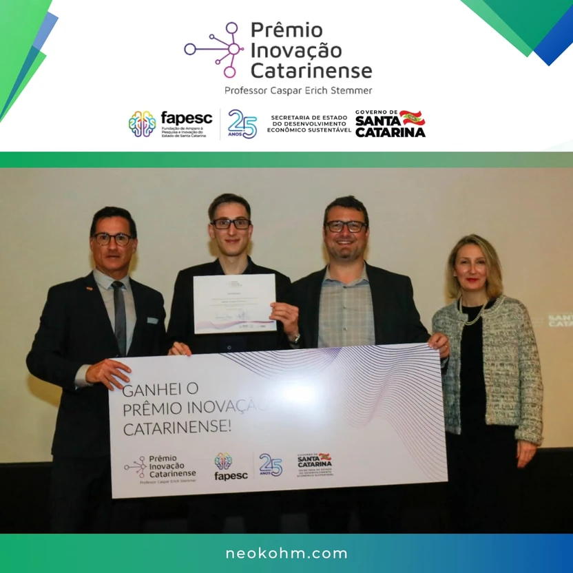 Três homens seguram uma placa grande do Prêmio Inovação Catarinense ao lado de uma mulher; um deles também mostra um certificado.